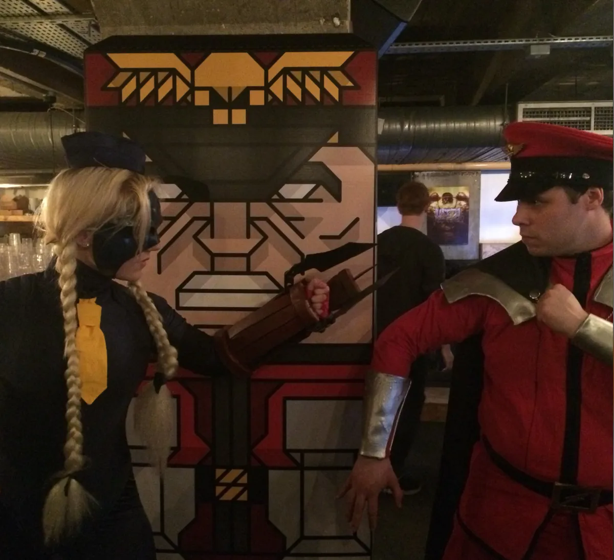 Two cosplayers pose with a giant M. Bison at the launch event